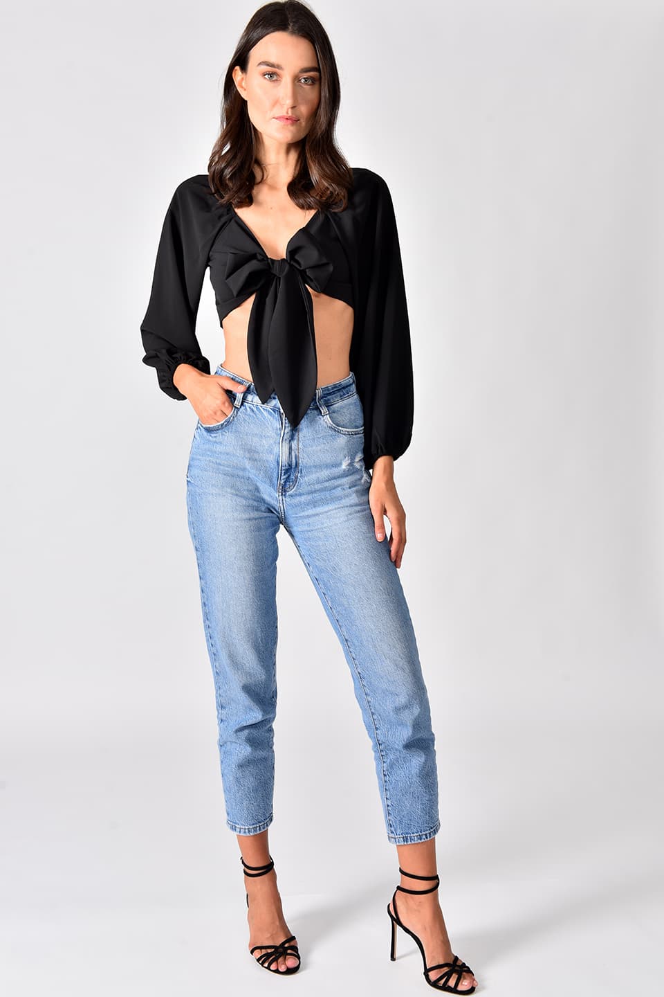Model wearing trendy crop top in black color, in pose for full-body view