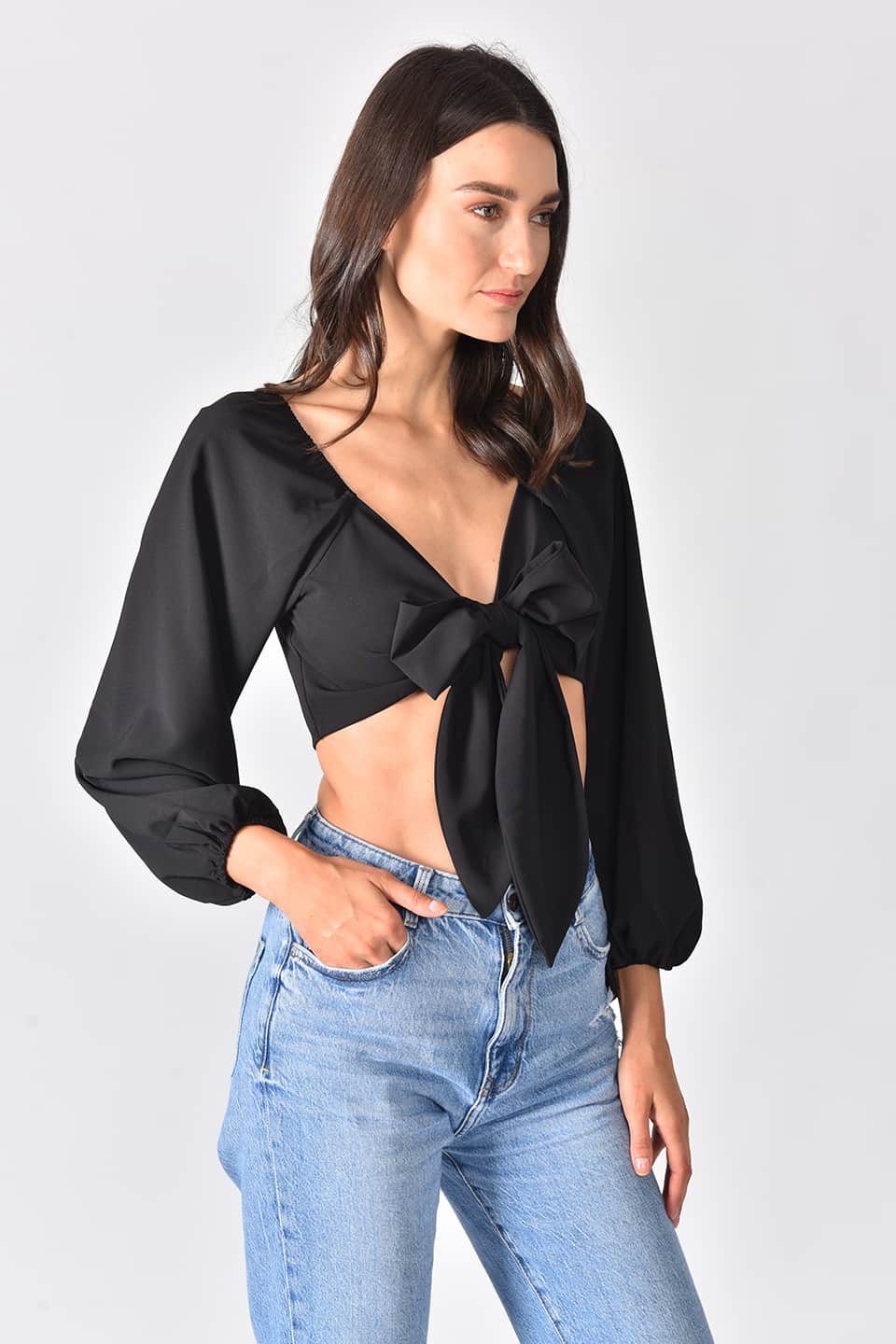 Model wearing trendy crop top in black color, in pose from left side