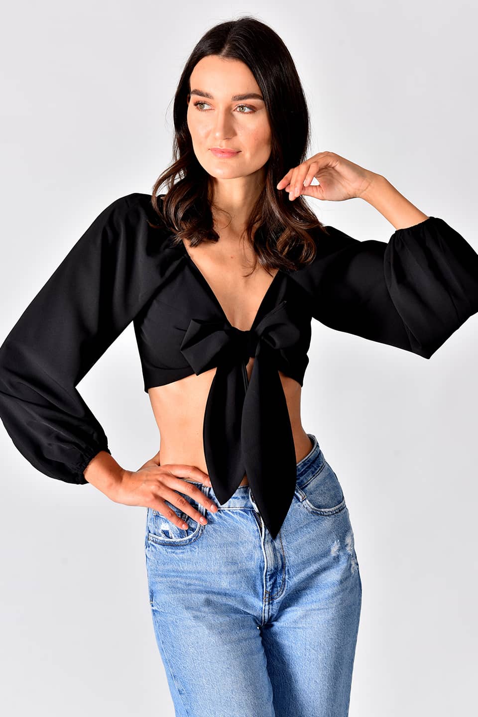 Model wearing trendy crop top in black color, in pose