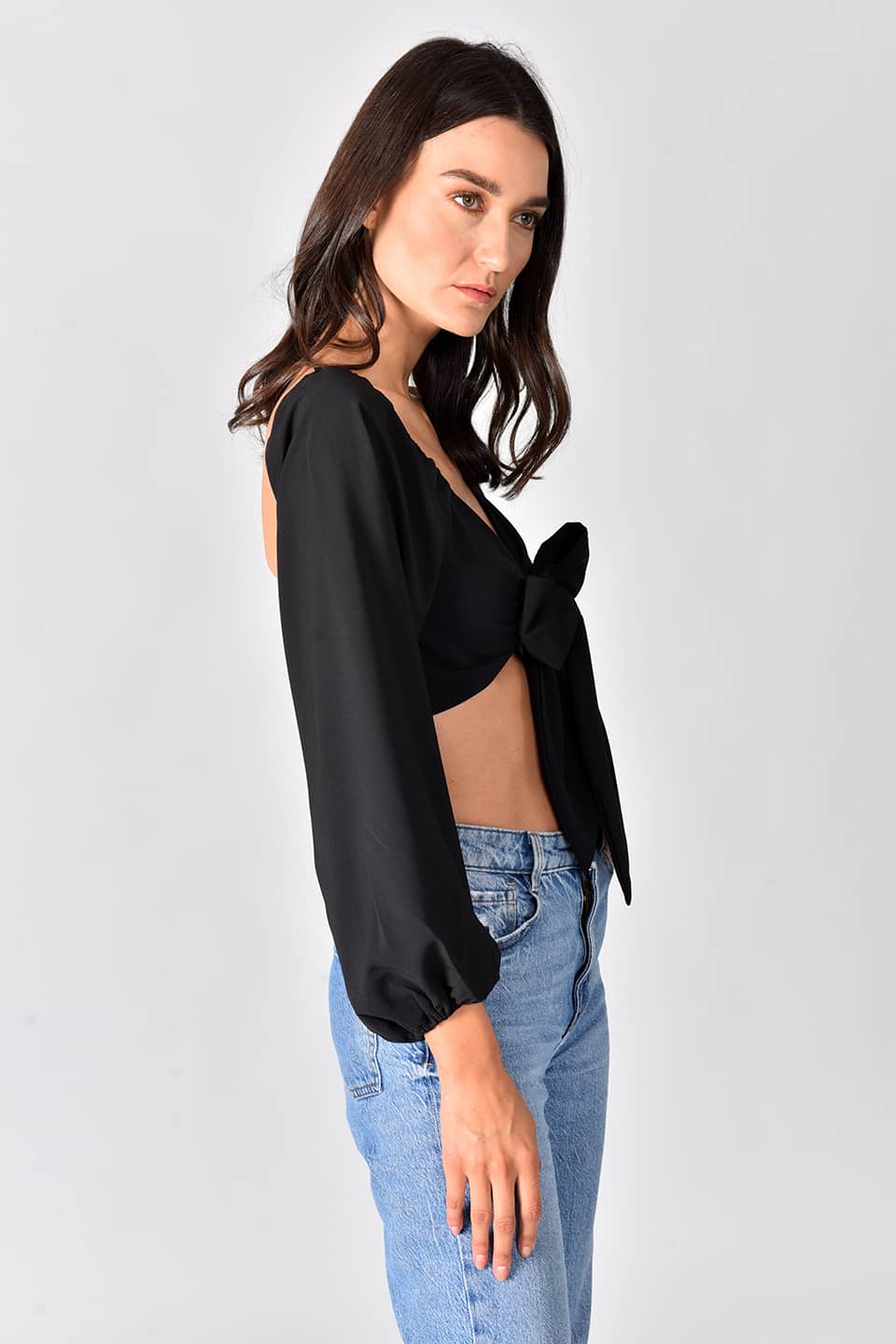 Model wearing trendy crop top in black color, in pose to show the side details