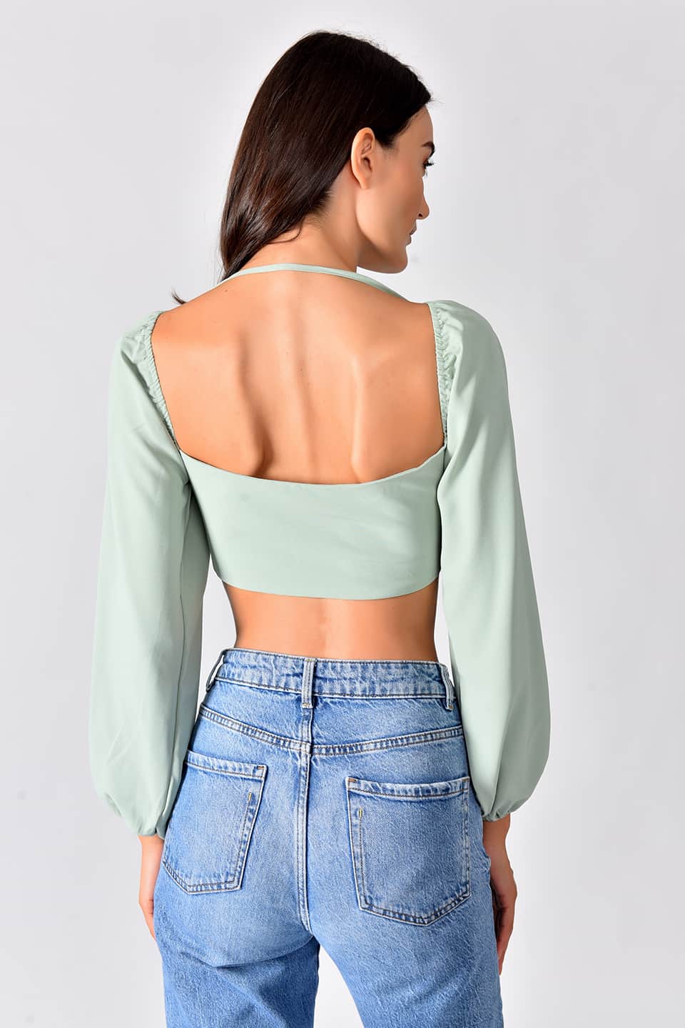 Model in pose from behind while wearing trendy crop top in green color