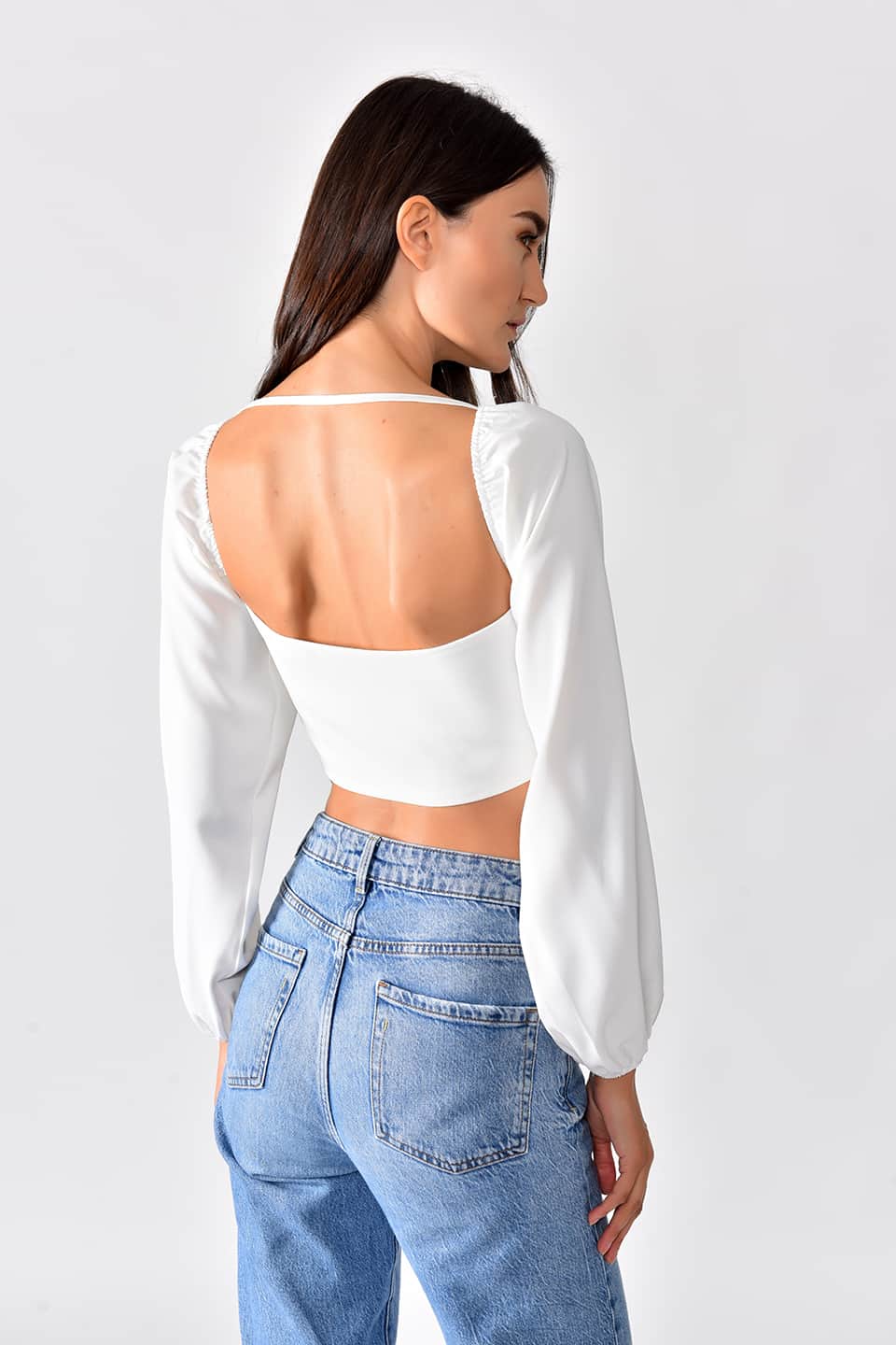 Model in pose for a back view, while wearing trendy crop top in white color