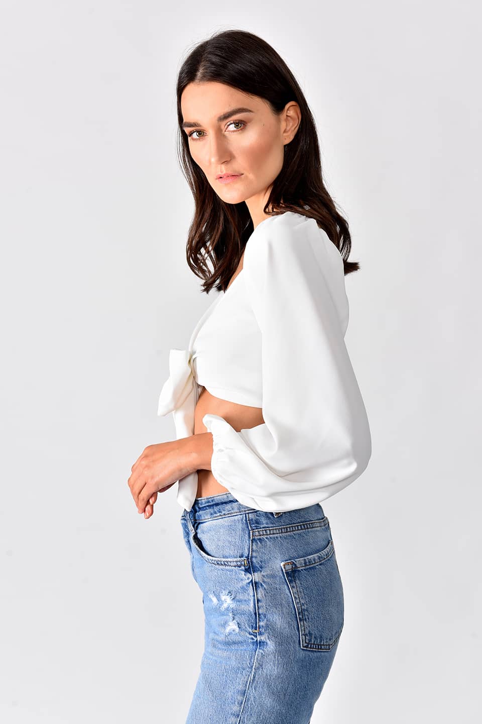 Model in pose from right side, while wearing trendy crop top in white color