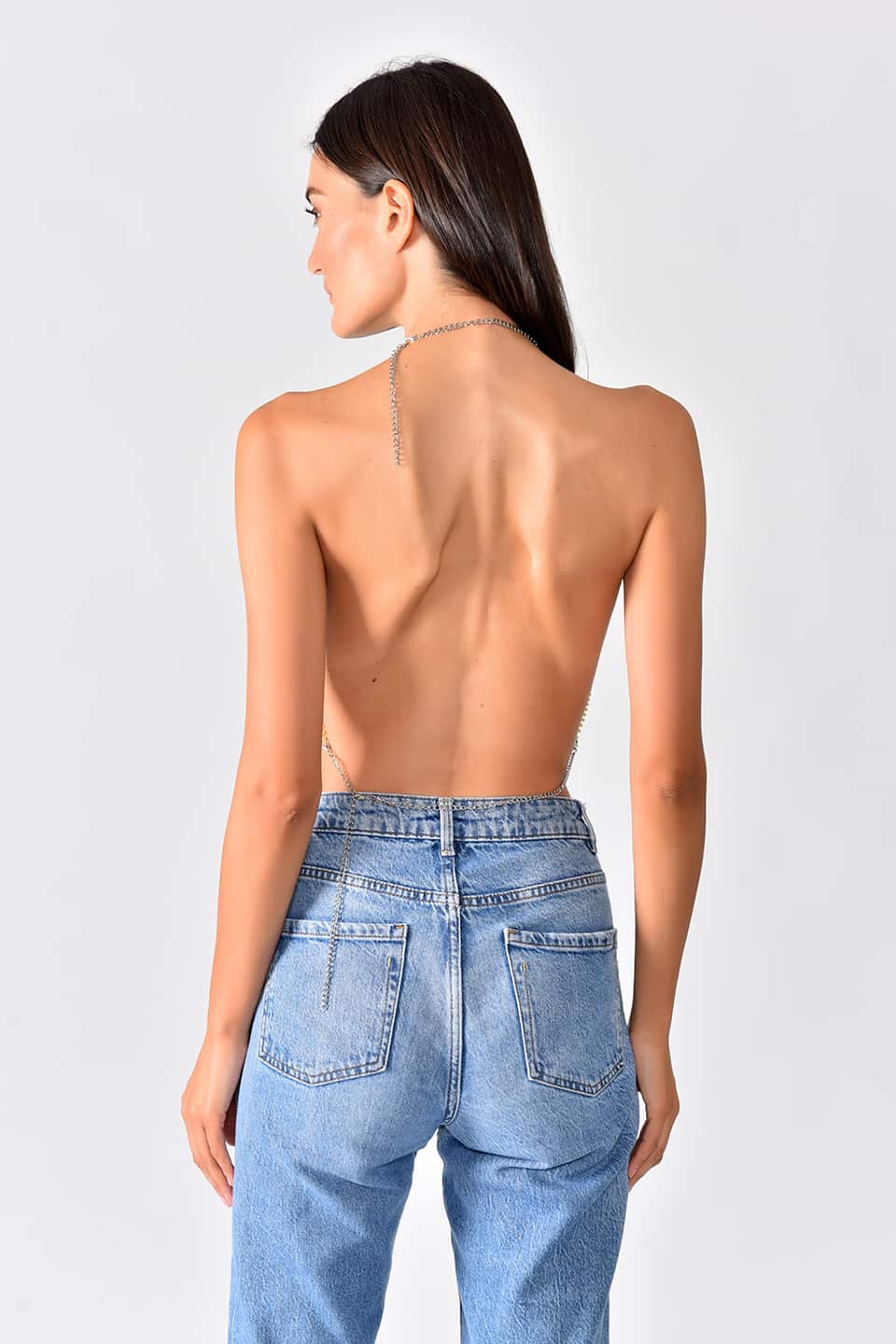 Model wearing shiny crop top in green-yellow gradient color, posing for a back view