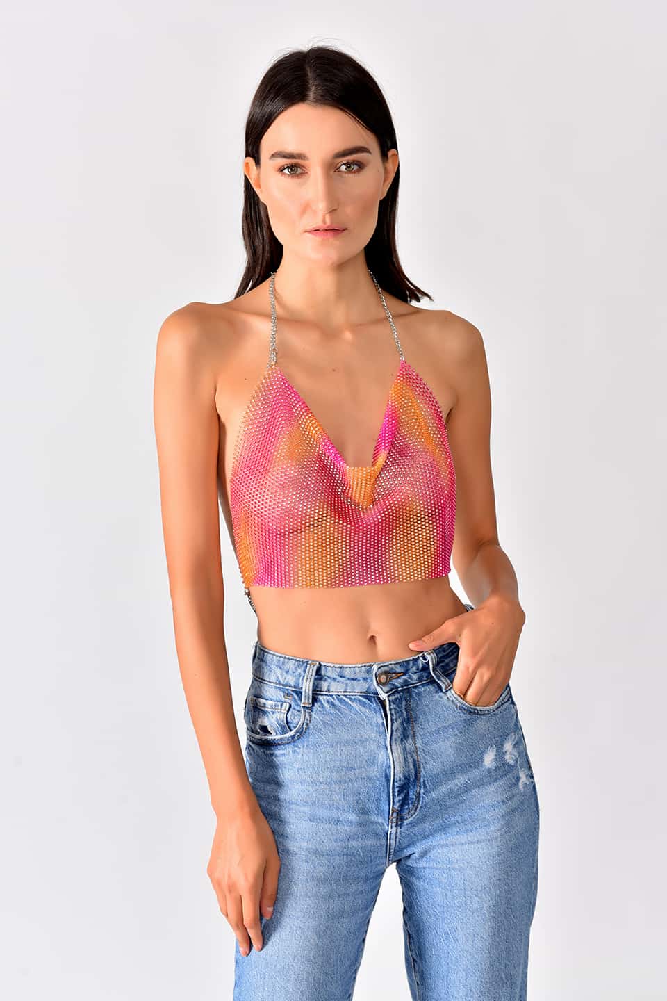 Model in natural pose is wearing shiny crop top in pink-yellow gradient color.