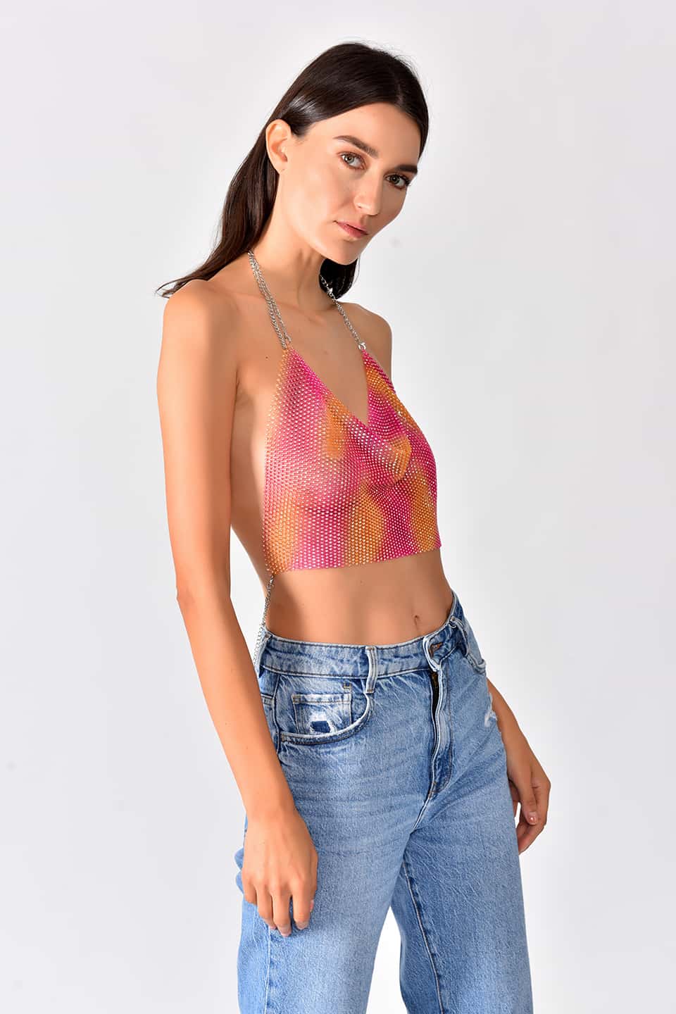 Model in pose is wearing shiny crop top in pink-yellow gradient color.