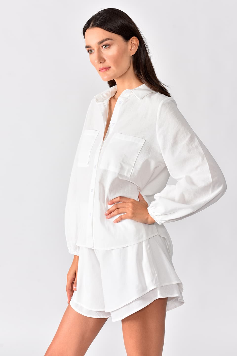 Model in pose for right details view, wearing beautiful loose white set, with wide leg double layered shorts.