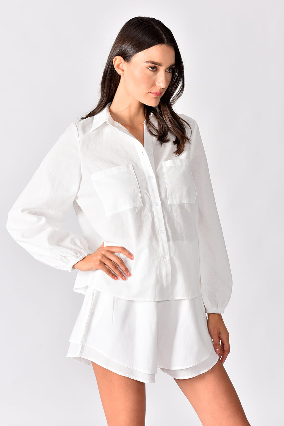 Model in pose, wearing beautiful loose white set, with wide leg double layered shorts.