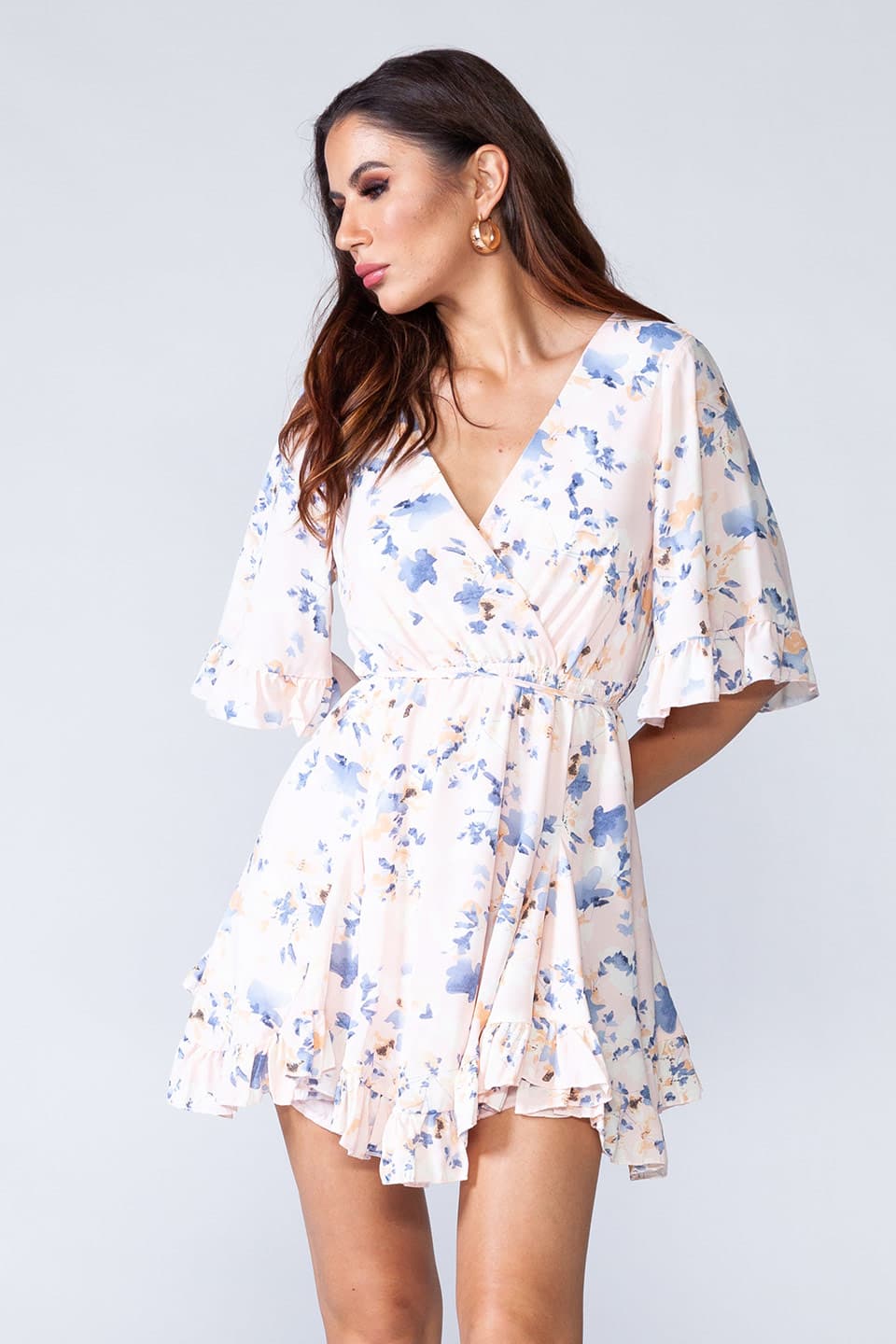 Whitish floral ruffled summer mini dress with V-neck and short sleeves. Model natural posing