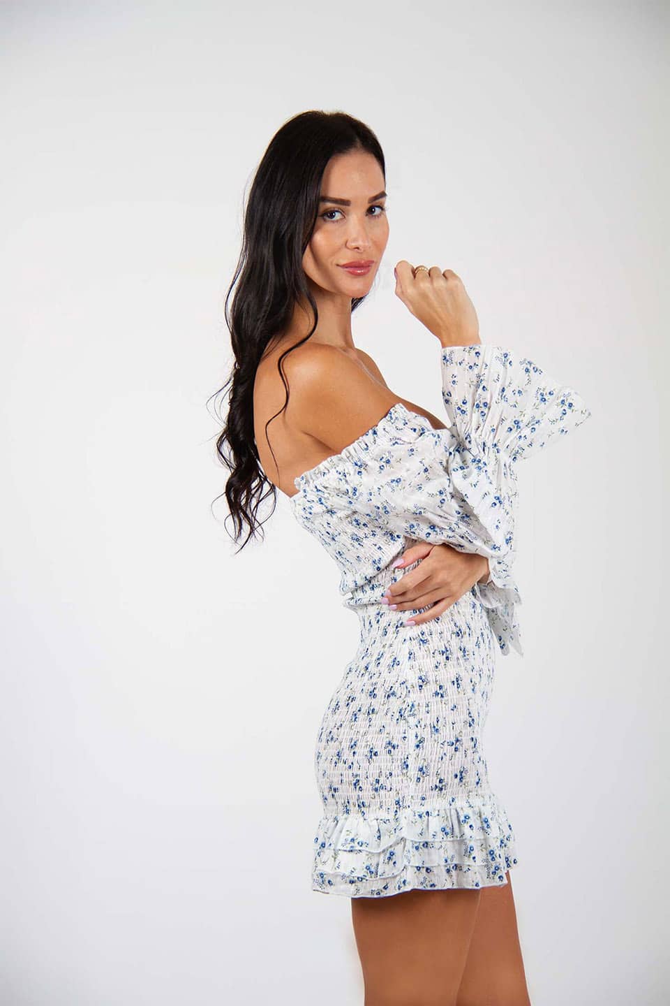 Off-shoulder floral print mini dress, trendy and sleeveless. Model posing for side view