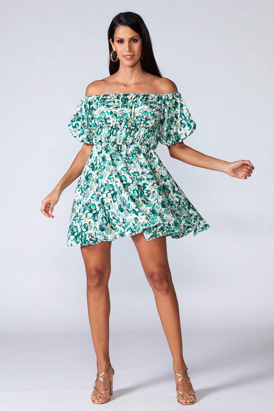 Off-shoulder mini dress with elastic waist and ruffled bottom of the skirt. Model posing for front, full body view