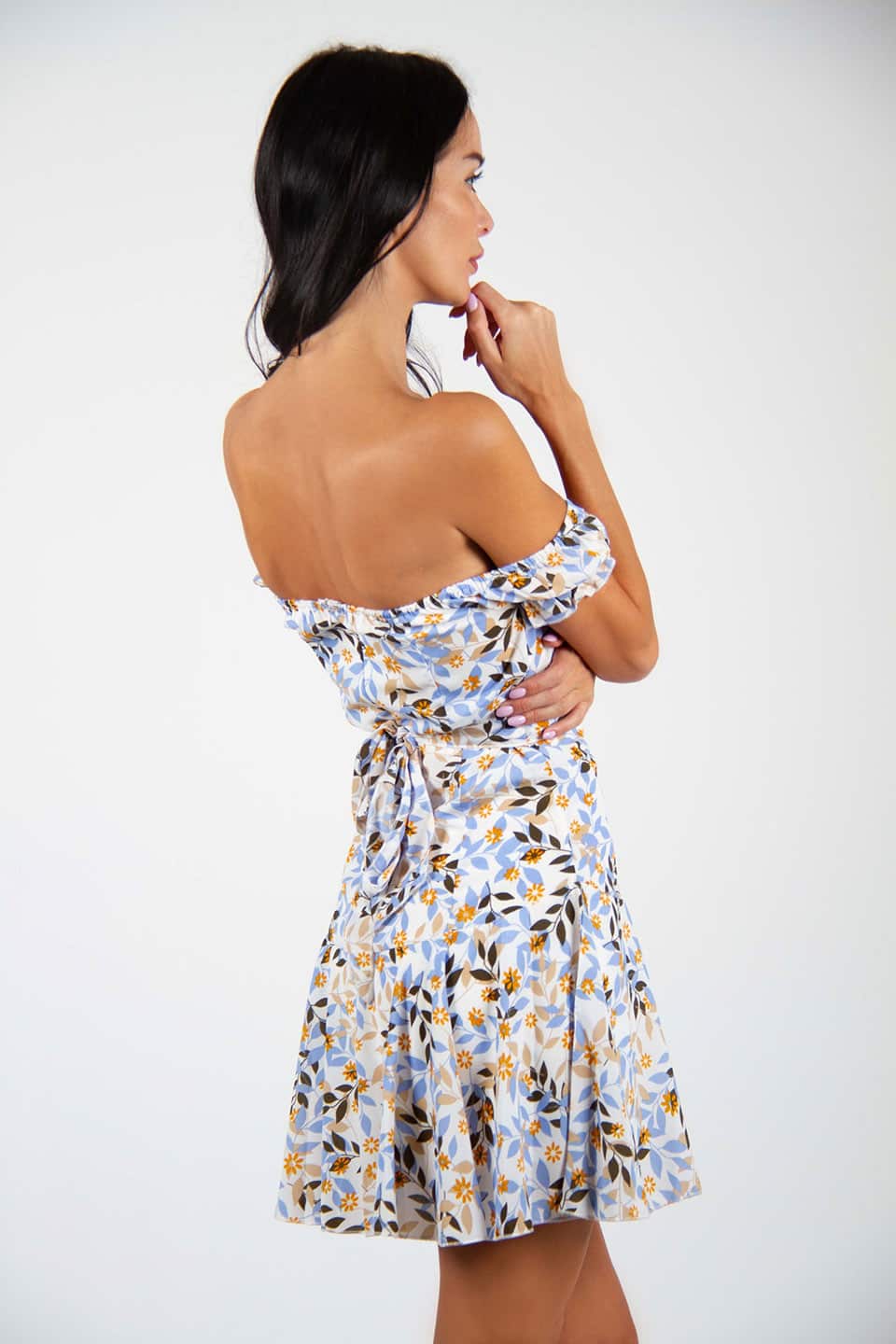 Trendy and colorful floral print mini dress with belt. Model posing for behind view