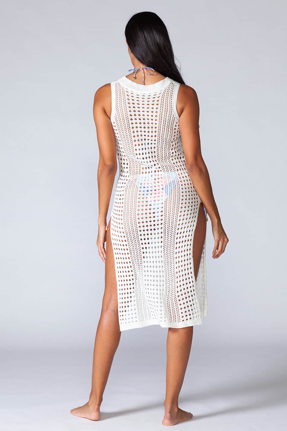 Hollowed-out kaftan in white color, sleeveless and stretchable. Model posing from behind