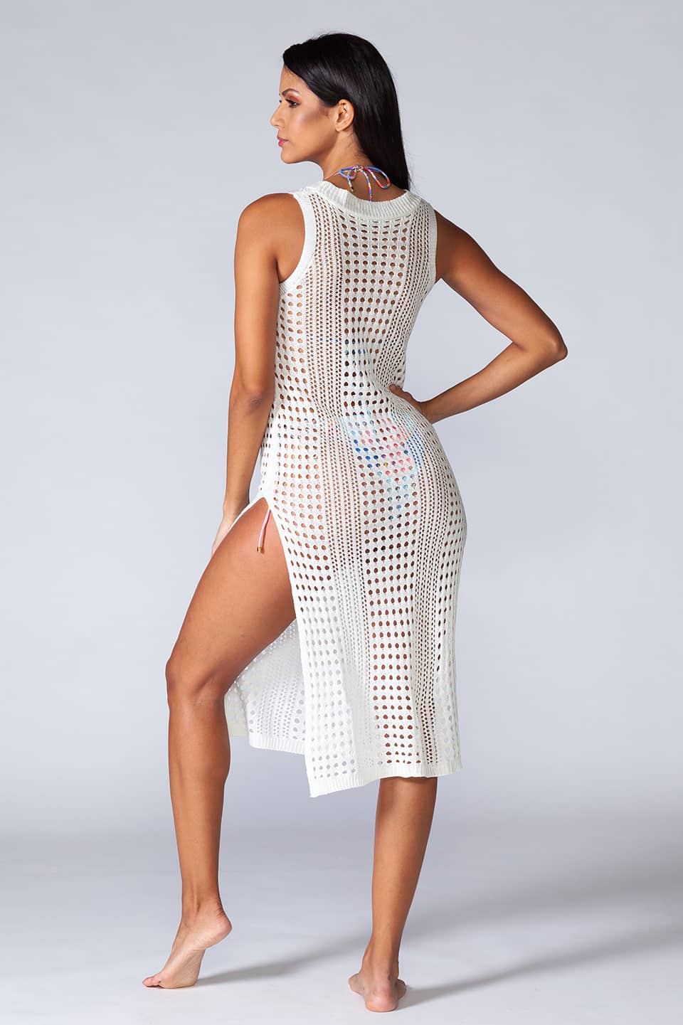 Hollowed-out kaftan in white color, sleeveless and stretchable. Model in back view