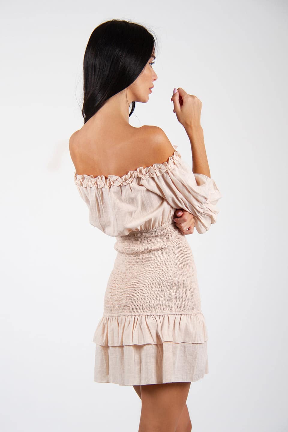 Model wearing off-shoulder mini dress with a linen texture. Side view