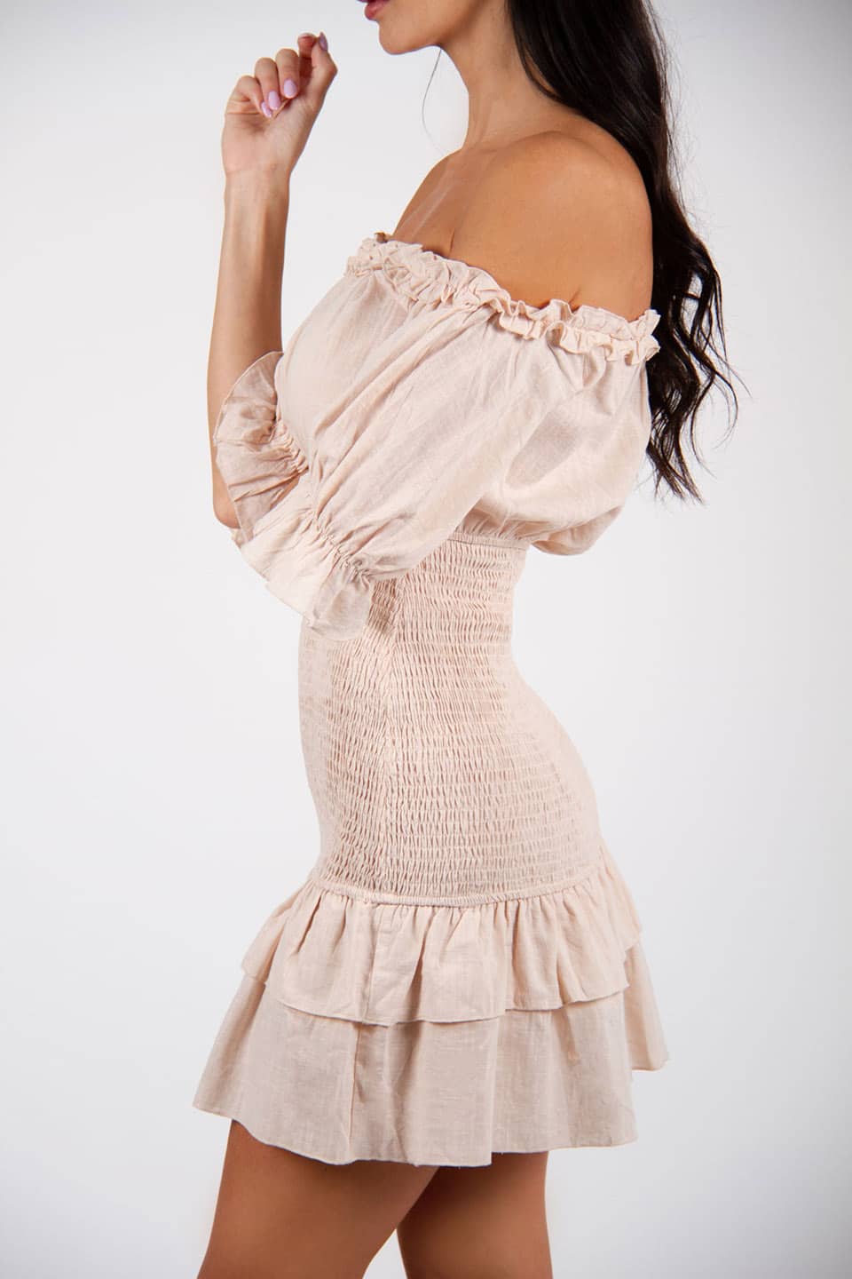 Model wearing off-shoulder mini dress with a linen texture. Left side view