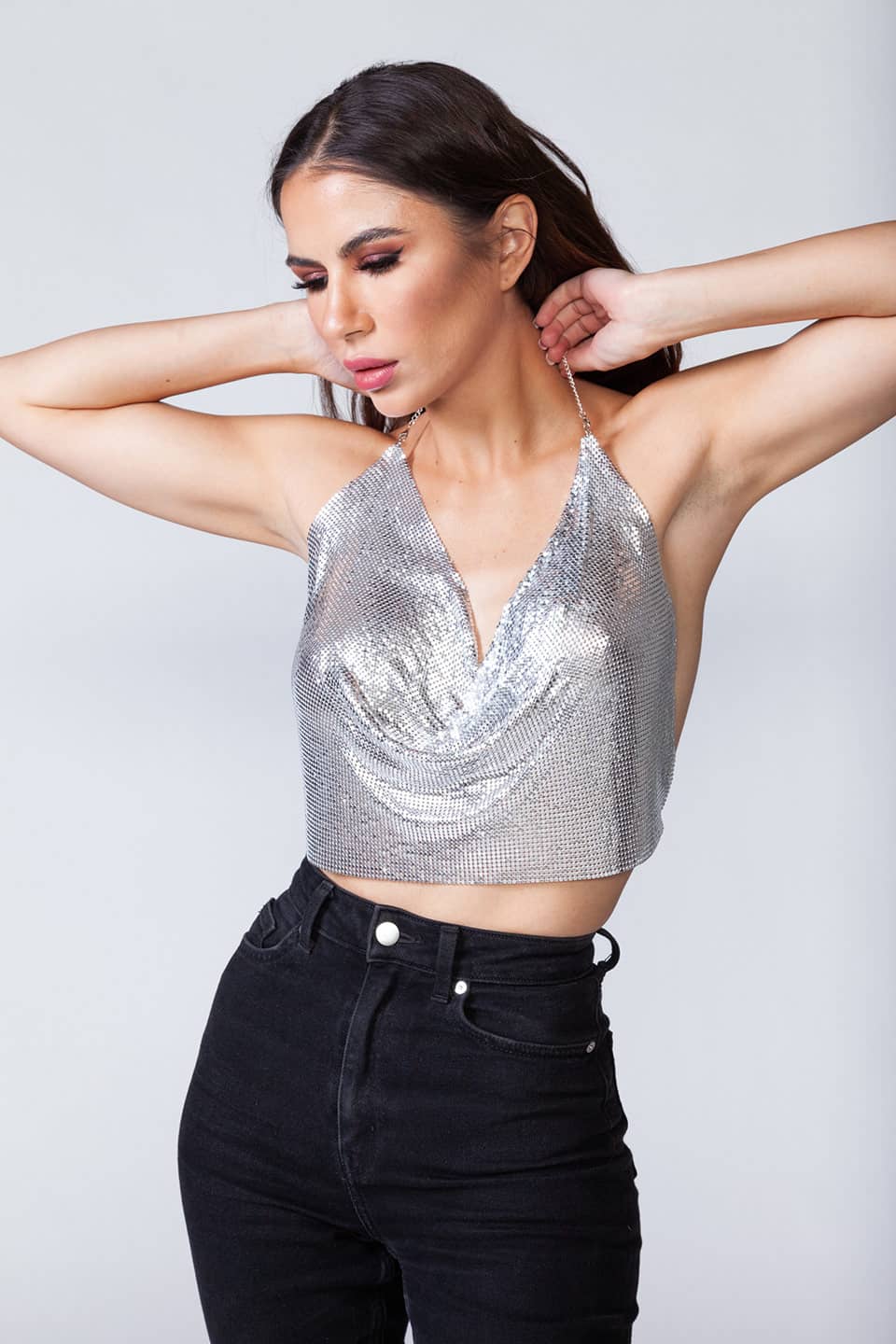 Model wears metal crop top in silver color, showing material finitures