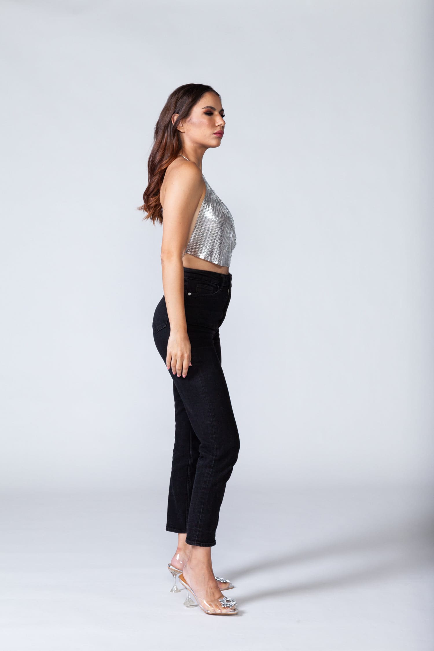 Model wears metal crop top in silver color, posing for side view