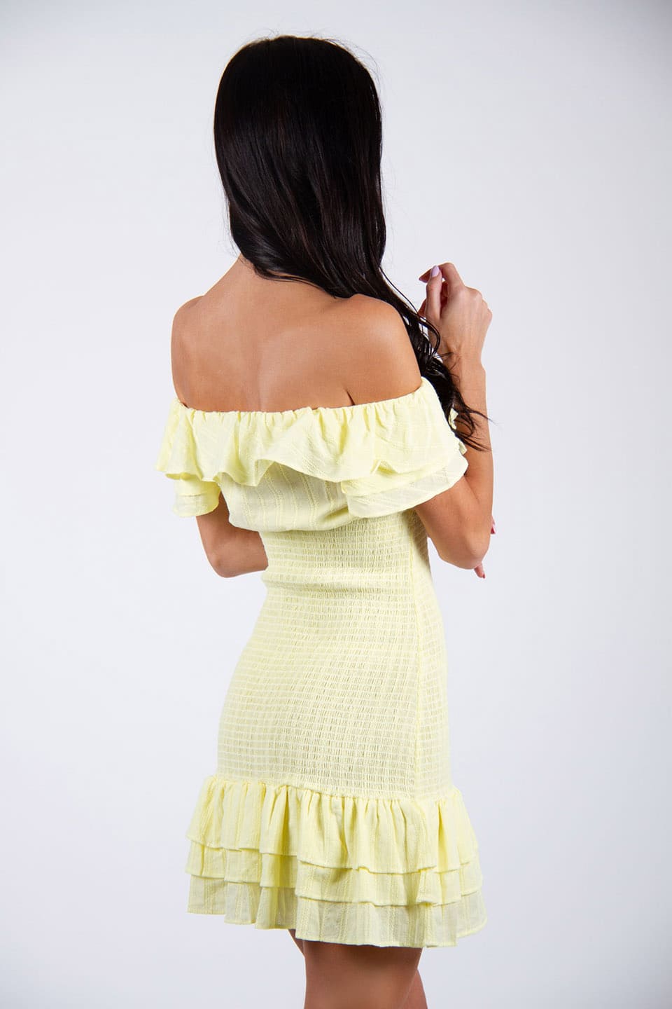 Model wears off-shoulder elasticated dress in yellow color, posing from behind