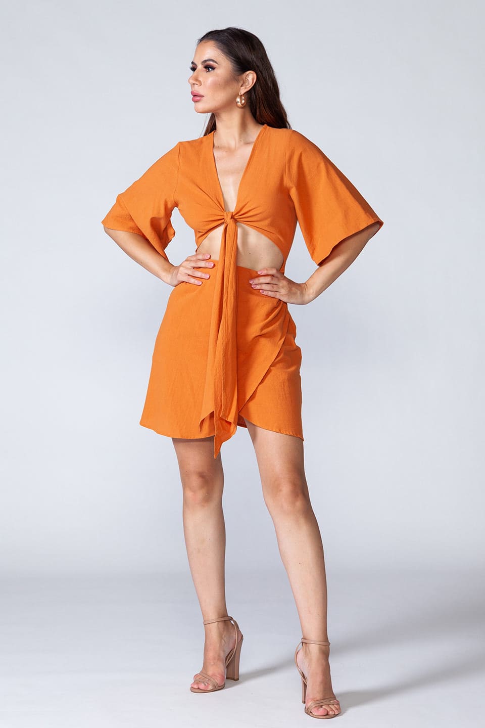 Model wearing cotton mini dress with open cut-out front that ties in knot, posing for front full body view