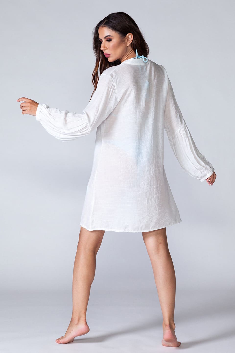 Model wearing long sleeved beach shirt kaftan style, posing from behind full body